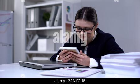 Imprenditrice guardando ragazza foto mancanti figlia, chiuso portatile per break Foto Stock
