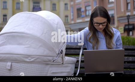 Nervoso madre di lavoro cercando fine progetto su laptop e alimentazione bambino con latte Foto Stock