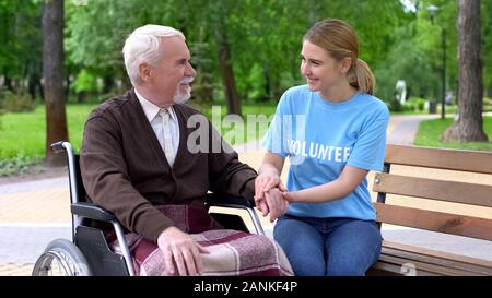 Tipo donna giovane volontario t-shirt tenendo disattivato maschio lato supporto paziente Foto Stock
