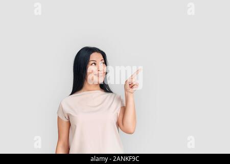 Freestyle. Donna asiatica in piedi isolato su bianco rivolto a parte lo spazio sorridendo felice Foto Stock