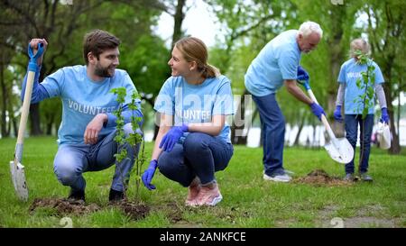 Gruppo di volontari eco piantare alberello nel parco pubblico, la natura cura Foto Stock