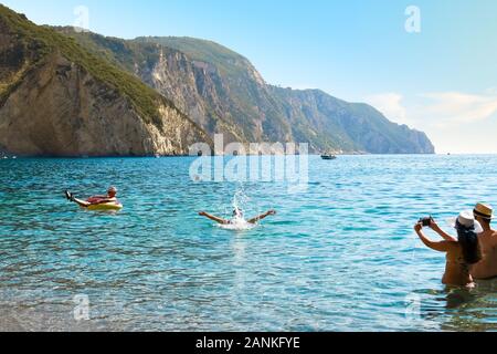 I turisti giocano in mare a Chomi o Paradise Beach sull'isola greca di Corfù. Foto Stock