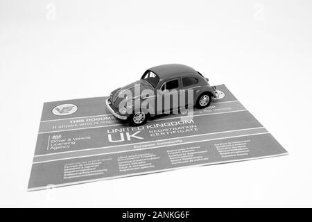 Giocattolo rosso Volkswagen Beetle con un documento V5C. Foto Stock