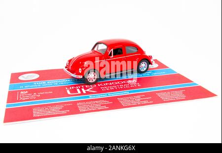 Giocattolo rosso Volkswagen Beetle con un documento V5C. Foto Stock