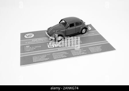 Giocattolo rosso Volkswagen Beetle con un documento V5C. Foto Stock