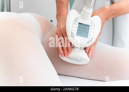 Donna in speciale tuta bianca getting anti cellulite massaggio in una spa salone. Gpl e body contouring il trattamento in clinica Foto Stock