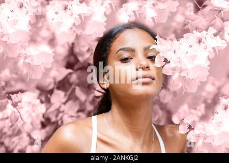 Bella giovane donna tra fiori di colore rosa Foto Stock