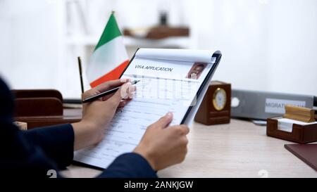 Immigrazione femminile inspector verifica visa application office, bandiera italiana Foto Stock