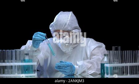 Assistente di laboratorio indossare tuta protettiva e studiare le provette con virus Foto Stock