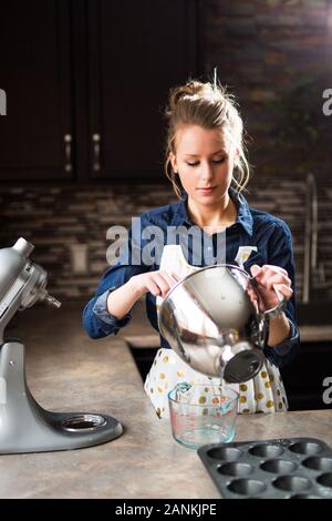 Una giovane donna che mescola gli ingredienti nel suo mixer Foto Stock