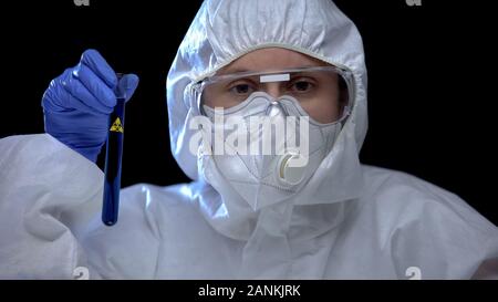 Lavoratore di laboratorio scientifico tenendo il tubo di prova con pericolo biologico segno, danni Foto Stock