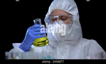Lavoratore di laboratorio scientifico di analisi del liquido infiammabile nel pallone, accenditore tossici Foto Stock
