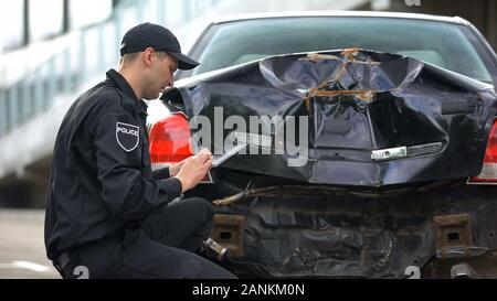 Lavoratore di pattuglia di riempimento relazione tablet online presso auto scena di collisione, lavoro di polizia Foto Stock