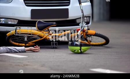 Bicicletta e femmina giacente su asfalto hit auto, inconscio vittima di incidente, sicurezza Foto Stock