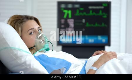 Il pianto della donna nella maschera di ossigeno guardando la telecamera, stabilizzato dopo la chirurgia, la salute Foto Stock