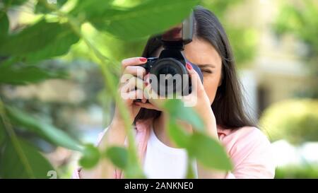 Fotografo femmina con telecamera professionale rendendo le foto a City Park Foto Stock