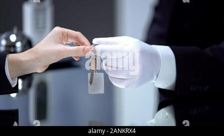 Hotel a mano di amministratore in guanto dando lady tasto sulla catena, servizio vip, lusso Foto Stock