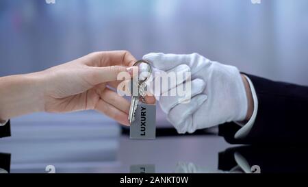 Hotel receptionist dando a mano portachiavi visitatore, un servizio di alta qualità, lusso Foto Stock