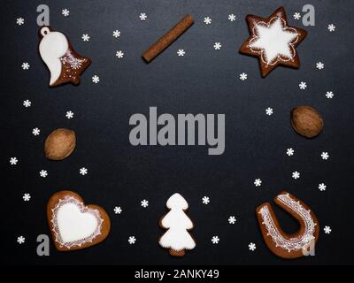 Deliziosa casa natale gingerbread cookies in forma di albero, star, bell, cuore e a ferro di cavallo su sfondo nero con spazio per il testo Foto Stock