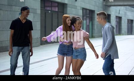 Multietnica adolescenti abbracciando camminando sulla strada, tempo libero insieme, gioventù Foto Stock