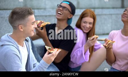 Gruppo di adolescenti in buon umore sinceramente ridendo durante la pizza, amicizia Foto Stock