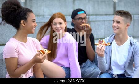 Giovani amici multietnica ridere godendo la pizza, adolescenza positività, divertente Foto Stock