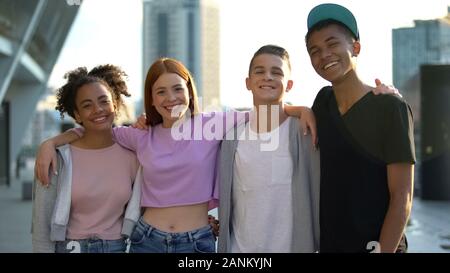 Allegro multi-razziale amici abbracciando sorridente fotocamera, teenage stare insieme Foto Stock
