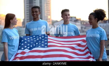 Gioiosi volontari multietnica holding bandiera americana, progetto di beneficenza, supporto Foto Stock