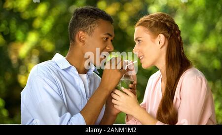 Gli adolescenti in amore di bere cocktail attraverso cannucce da un vetro, data romantico Foto Stock