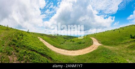 Mountain strada sterrata paesaggio. percorso attraverso i prati erbosi su dolci colline. ridge in distanza. verde paesaggio dei Carpazi. nuvoloso estate meteo Foto Stock