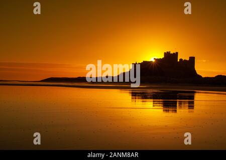 Inverno alba sopra il castello di Bamburgh uno dei più iconica stupende viste sul castello nel Regno Unito arroccato su uno sperone di origine vulcanica sulla costa di Northumberland Foto Stock