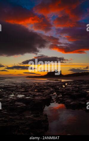 Inverno alba sopra il castello di Bamburgh uno dei più iconica stupende viste sul castello nel Regno Unito arroccato su uno sperone di origine vulcanica sulla costa di Northumberland Foto Stock