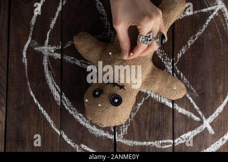 Bambola Voodoo su uno sfondo di legno con illuminazione spettacolare. Il concetto di stregoneria e di arte nera e l'occulto. Bambola Burlap sullo sfondo di un Foto Stock