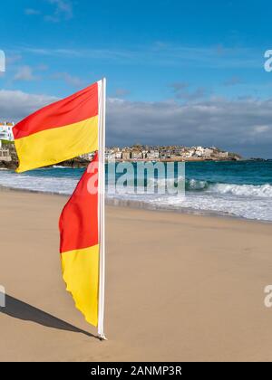 Bagnino bandiere soffia nella brezza di mare marcatura safe area nuoto, Porthminster Beach, St Ives, Cornwall, Inghilterra, Regno Unito. Foto Stock