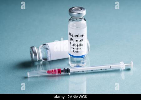 Il morbillo parotite rosolia fiale di vaccino con siringa su sfondo turchese Foto Stock