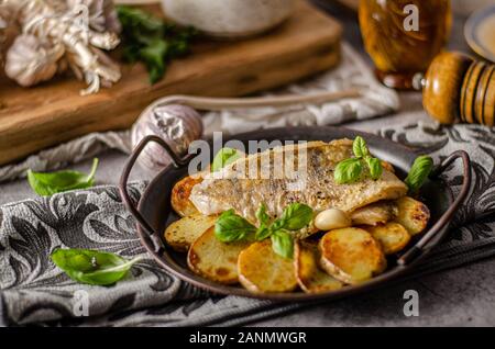 Delizioso pesce con patate arrosto e bio aglio Foto Stock