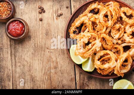 Frittura di anelli di totano fritto con calce su sfondo di legno Foto Stock