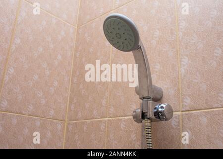 Doccia con getto a pioggia in bagno consegna sulla piastrella arancione per la pulizia e la balneazione. Plumbing, standard igienici e concetti di residenza. Foto Stock
