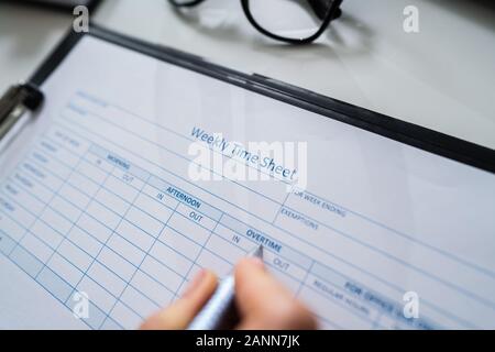 Close-up di persona la mano vuota di riempimento tempo settimanale foglio con penna Foto Stock