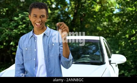 Giovane maschio nero tenendo premuto il tasto di Automobili, trasporti acquisto, patente di guida Foto Stock
