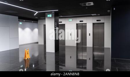 Moderno edificio di uffici, ascensore bianco e nero con porte scorrevoli in acciaio inox e pavimento in marmo. Ingresso banca o altra istituzione. Galleggiante bagnato Foto Stock