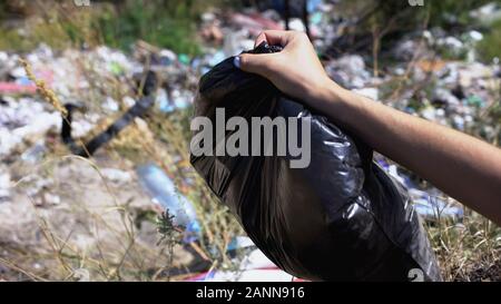 Mano Womans sacco di contenimento dei rifiuti contro la discarica in foresta, sistema ecologico Foto Stock