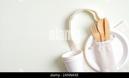 Bambù riutilizzabili set di posate monouso tazze di carta e la piastra, cotone borsa su sfondo verde. Vista da sopra con copia spazio. Rifiuti Zero concetto. Eco store Foto Stock