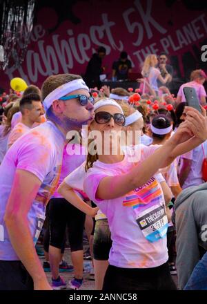 Uomo e donna celebrano il completamento della Color Run di Birmingham 2015 prendendo un selfie sul telefono cellulare mentre si tirano le espressioni facciali sciocche Foto Stock