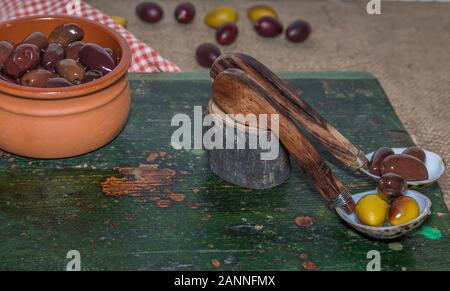 Le olive. Kalamata olive greche in conchiglia cucchiai con recipiente di ceramica sulla sinistra. Immagine di stock. Foto Stock