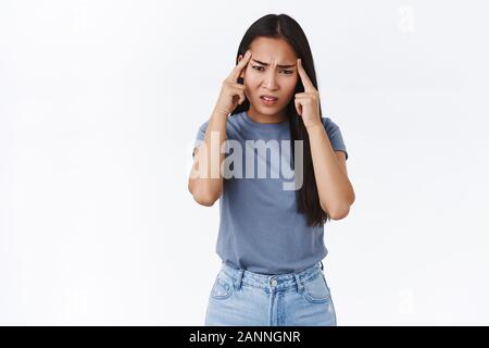 Turbato ill carina ragazza asiatica con scuro taglio di capelli lunghi, accigliata perplessi o turbati, sensazione di disagio e indeciso, non riesco a pensare a una buona idea per proj Foto Stock