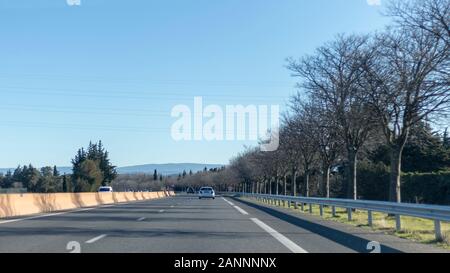 Provenza, Francia - Dicembre 2019 : strada asfaltata con vetture, attraverso la Provenza campagna in inverno pieno di sole giorno nel sud della Francia, Europa Foto Stock