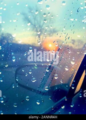 Finestra auto con gocce di pioggia sul bagnato giornata invernale al tramonto. Foto Stock
