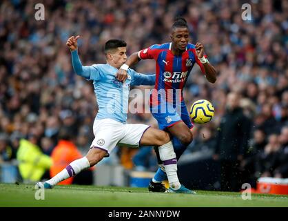 Manchester City's Joao Cancelo (sinistra) e il Palazzo di Cristallo di Wilfried Zaha (destra) battaglia per la palla durante il match di Premier League al Etihad Stadium e Manchester. Foto Stock