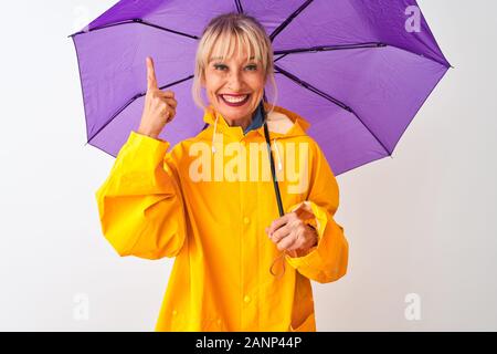 Medioevo donna che indossa la pioggia e il cappotto di viola ombrello isolato su sfondo bianco molto felice puntando con mani e dita Foto Stock